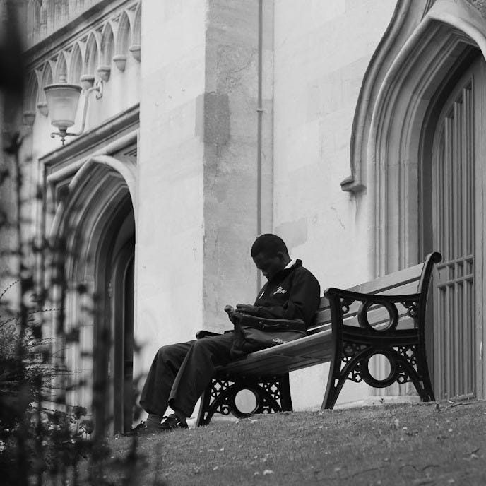 a person sitting on a bench in front of a building a person sitting on a bench in front of a building
