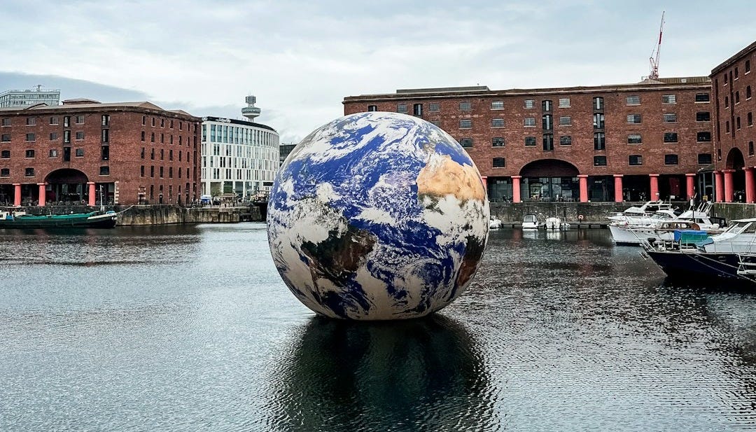 a large blue and white ball sitting on top of a body of water a large blue and white ball sitting on top of a body of water