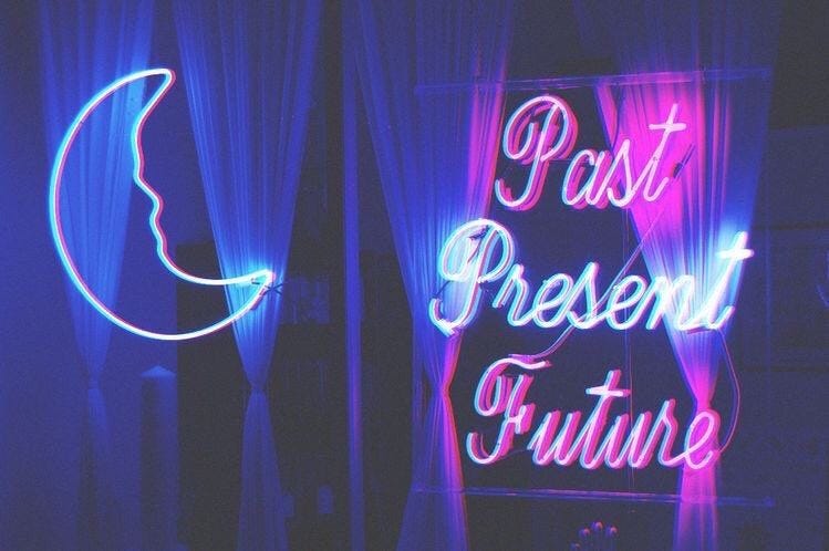Imagem da fachada de uma tenda de vidente, com as palavras Past Present Future em neon roxo e azul