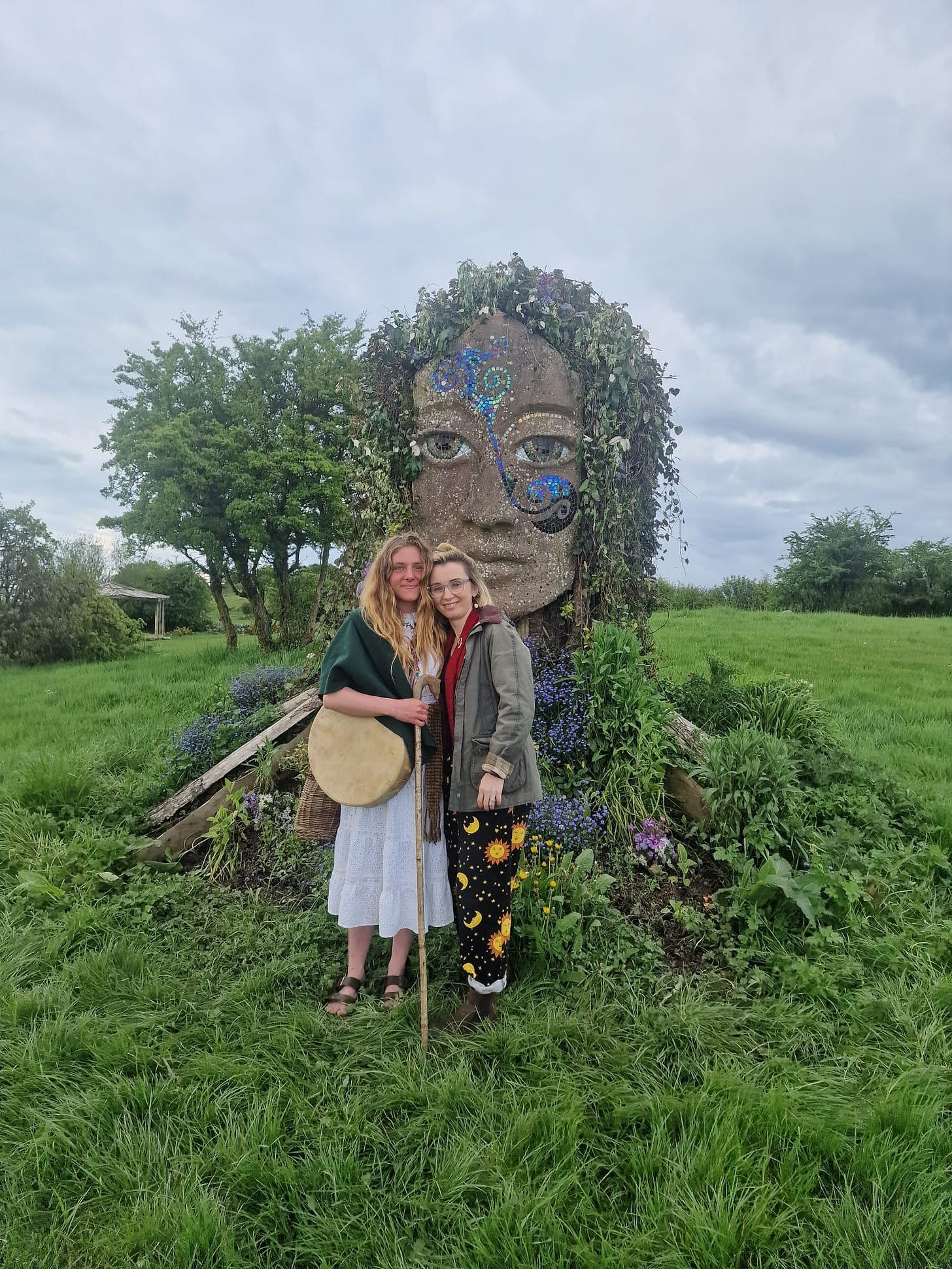 Aoife and Jen standing with Ériu goddess sculpture in Irish countryside