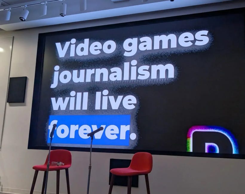 Two empty chairs and microphones stand in front of a projection screen that says "Video games journalism will live forever," Two empty chairs and microphones stand in front of a projection screen that says "Video games journalism will live forever,"