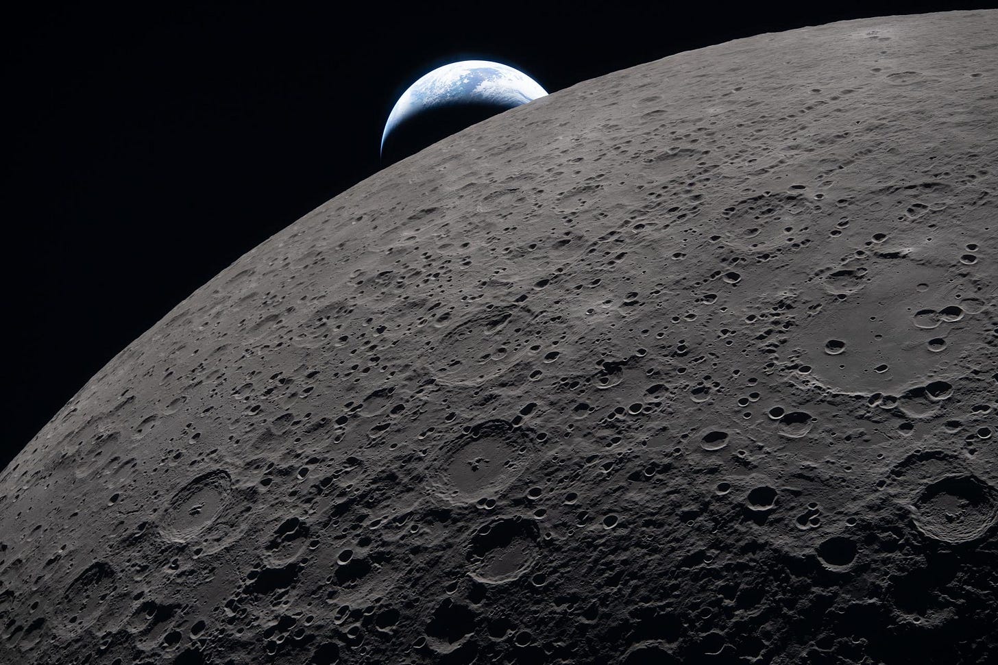 The lunar surface fills the frame in sharp detail while a distant Earth sets in the background