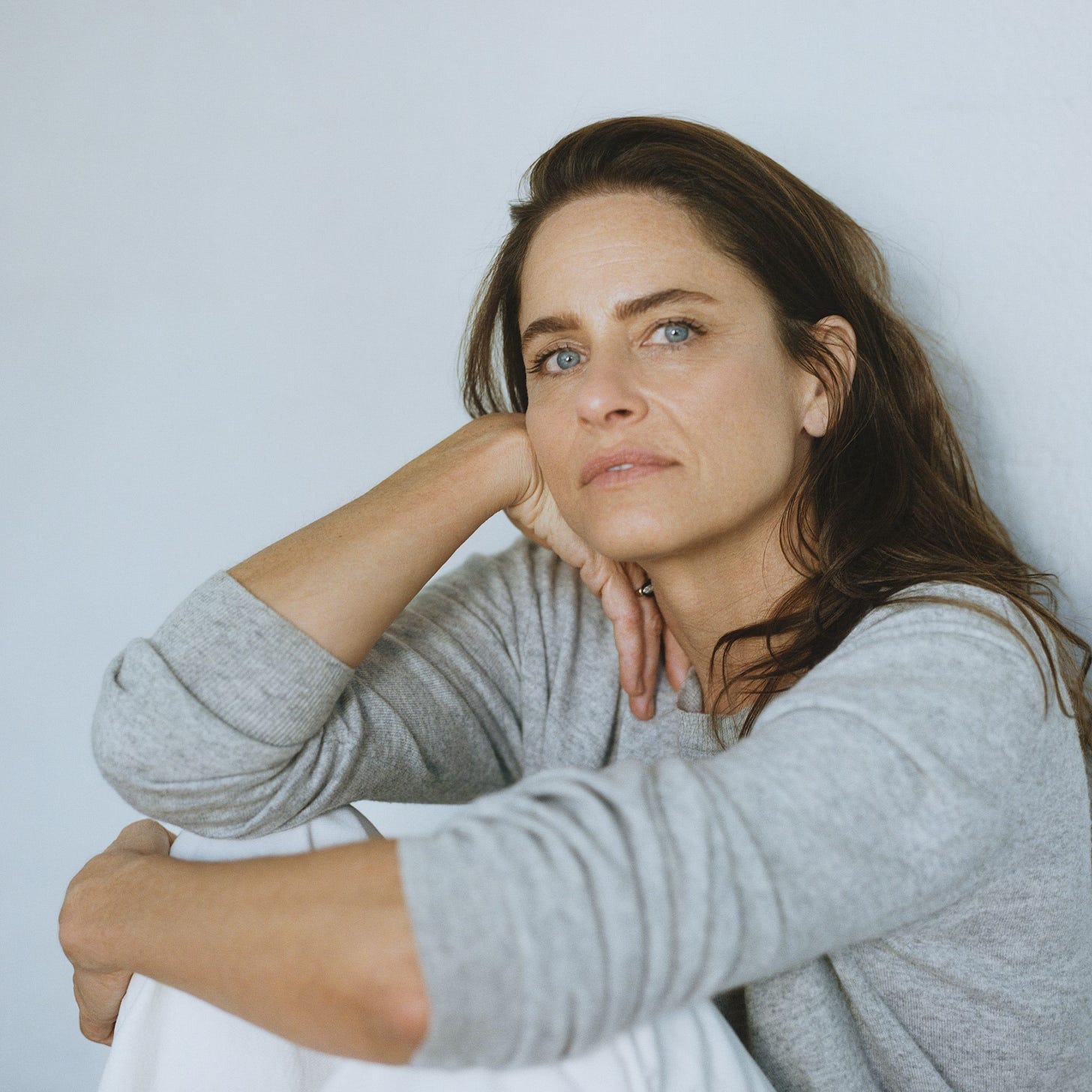 Amanda Peet looks toward the camera while her head rests on her hand.