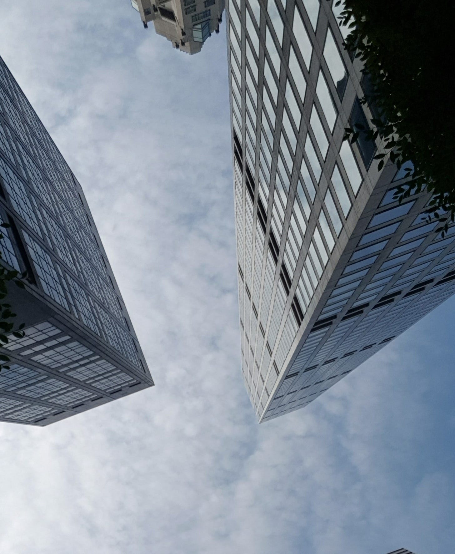 仰望視角下兩棟玻璃高樓在天空交會 仰望視角下兩棟玻璃高樓在天空交會
