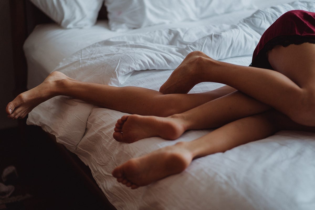 Naked legs entangled on a bed