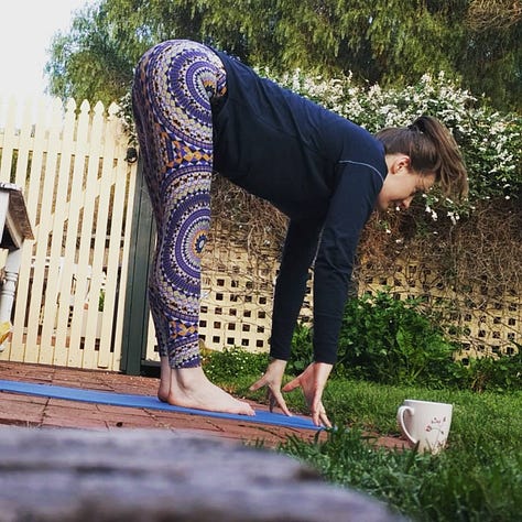 Image 1: Laura in side crow pose with split legs on a blue yoga matt outside on red pavers. Image 2: Black and white image of Laura outside on pavers in child's pose, a brick wall and sliding door in background. Image 3: Laura wearing colourful yoga pants in half lift, outside with a while mug at the top of her blue mat. Image 4: Laura in bambook pose in low light before sunrise in side, a wooden chair and rocking chair in the background. Image 5: Laura sitting on her blue yoga mat patting her white bun Percy on floating floors. Image 6: Laura in red pj pants with legs up the wall.