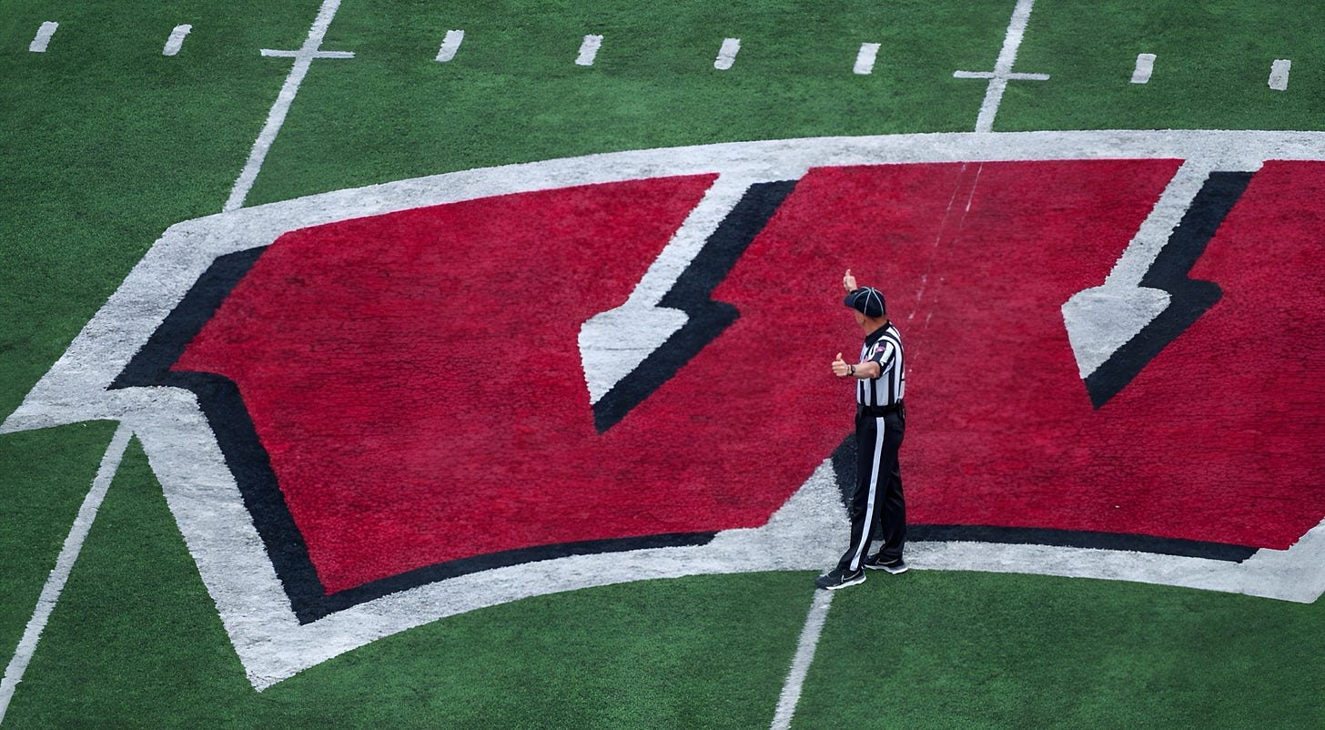 A game official stands at midfield on the 50-yard line at Camp Randall Stadium during a Wisconsin Badgers game.