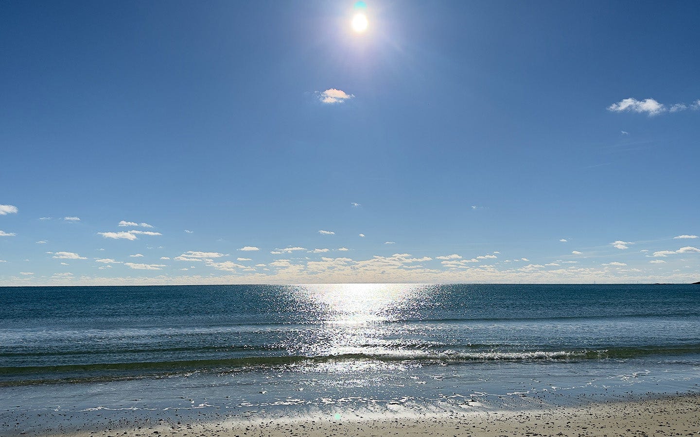 Goosewing beach scene with clear blue sky, sun, and ocean waves. Goosewing beach scene with clear blue sky, sun, and ocean waves.