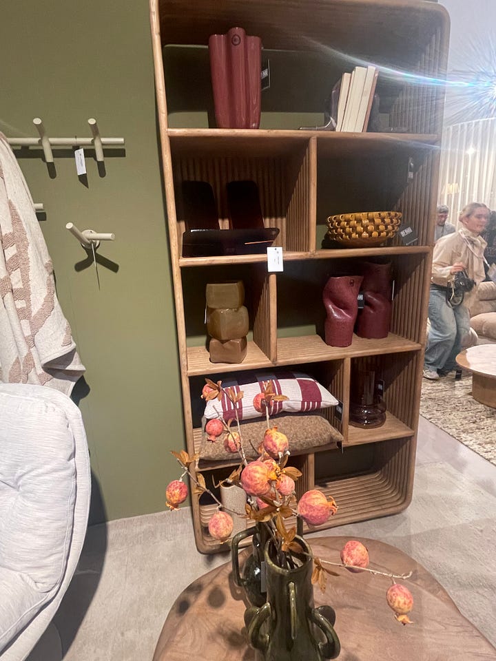 Open shelving display at Maison & Objet Paris 2026 featuring warm wood cabinetry, sculptural ceramics, decorative vessels, and earthy lifestyle accessories. Green lacquered storage furniture vignette at Maison & Objet Paris 2026 with rounded forms, modular cabinets, natural wood surfaces, and soft neutral wall textures.