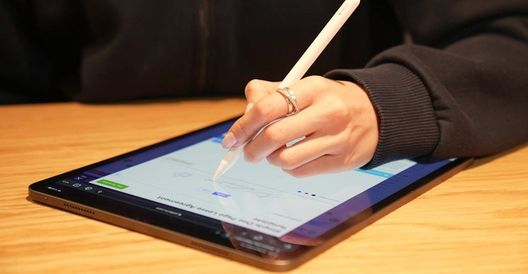 a person writing on a tablet with a pen