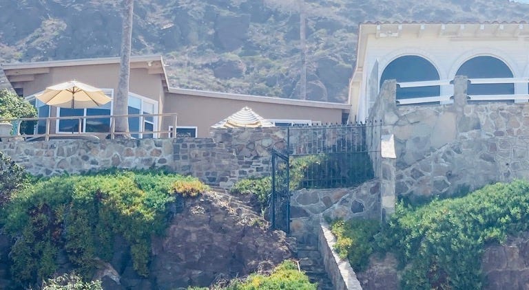 A beach house sits atop steps to the ocean