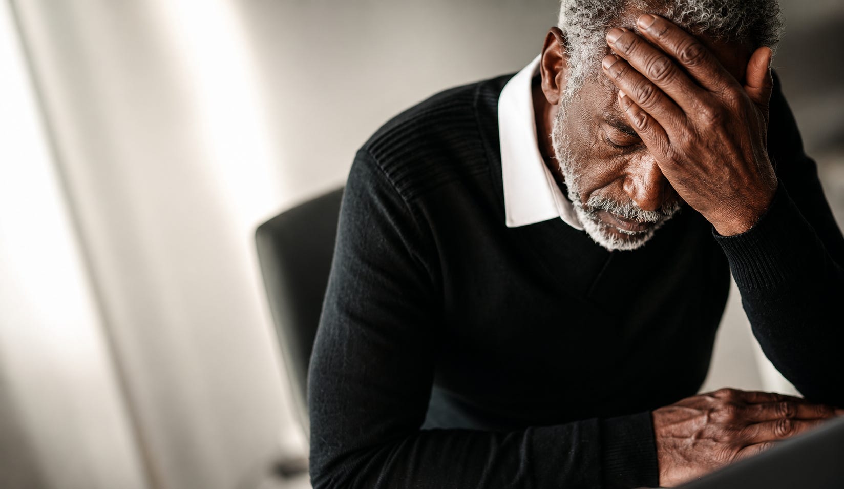 An older man sits quietly at his desk, overwhelmed by stress and deep in thought, with soft light falling across his face. An older man sits quietly at his desk, overwhelmed by stress and deep in thought, with soft light falling across his face.