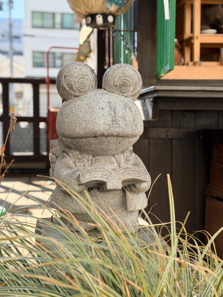Nawate Shopping Street in Matsumoto, left is a cat drinking water and right is a frog statue