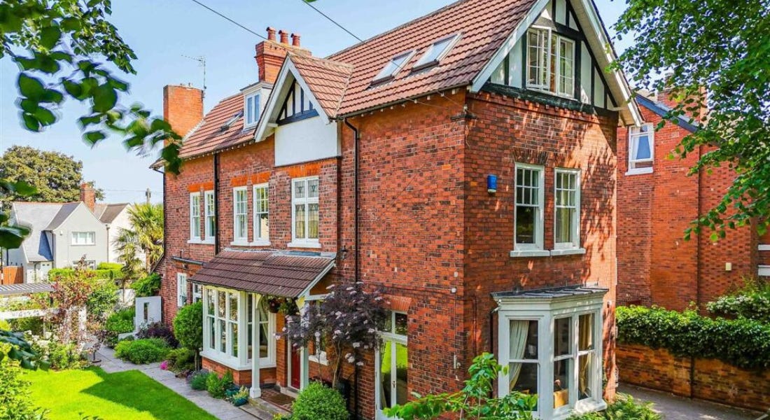 A large brick house with white windows, a green lawn, and trees around it A large brick house with white windows, a green lawn, and trees around it
