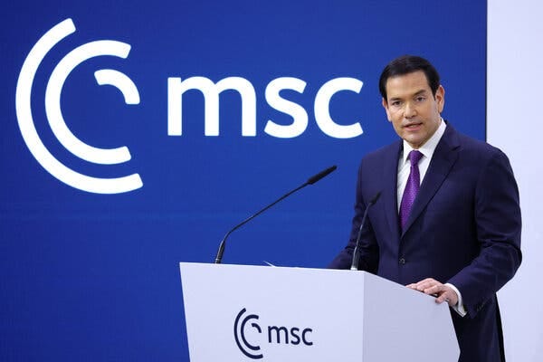Marco Rubio speaks at a white lectern with two microphones. A blue background with a white "msc" logo and text is visible behind him. Marco Rubio speaks at a white lectern with two microphones. A blue background with a white "msc" logo and text is visible behind him.
