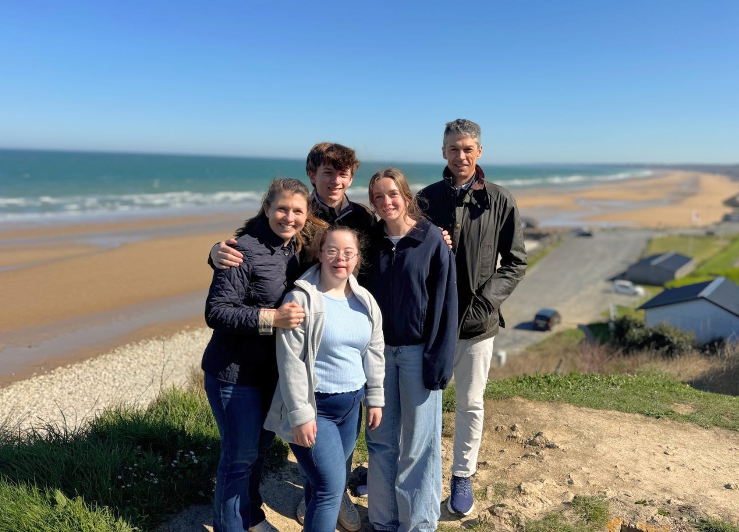 family posing on a bluff with the ocean in the background in France
