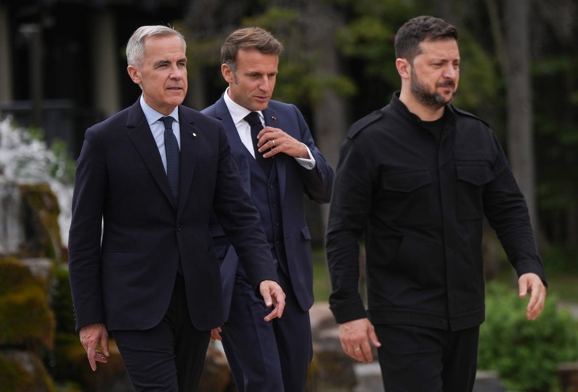 Three men walk outside. Two are wearing suits.