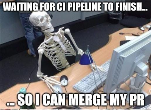 A skeleton sitting at an office desk, staring at a computer screen, waiting for a CI pipeline to finish so they can merge their pull request. DevOps struggles are real!