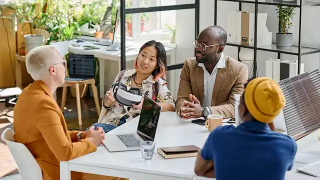Small team discussing brand decisions around a laptop in a bright meeting space