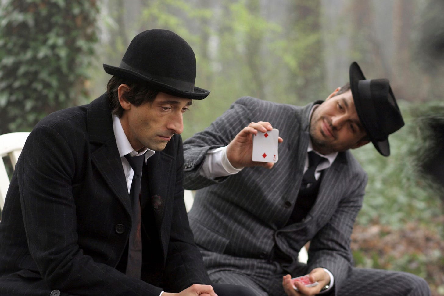 Shot from The Brothers Bloom. Bloom and Stephen sit on a bench at the zoo. Stephen shows Bloom the two of diamonds, asking if it's his card. Bloom looks away, dejected.