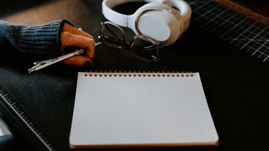 a notepad, pen and headphones on a table a notepad, pen and headphones on a table
