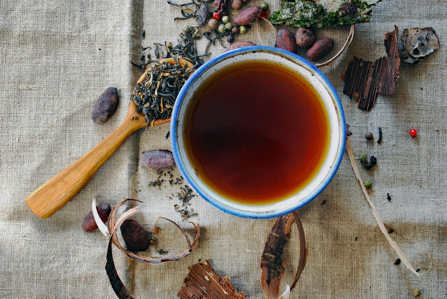 A cup of rich black tea featuring cocoa notes, loose leaves, and mixed herbs on a rustic surface. A cup of rich black tea featuring cocoa notes, loose leaves, and mixed herbs on a rustic surface.