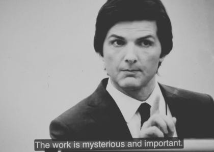 A man in a business suit holding up one finger with a caption that says "The work is mysterious and important"