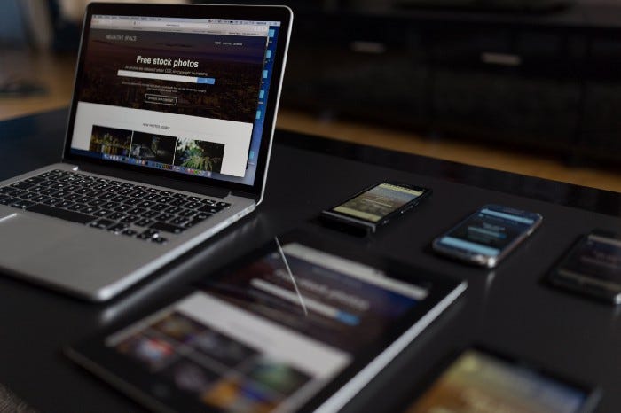 A laptop and several phones next to one another on a table. Each device is showing the same website, although at different resolutions. A laptop and several phones next to one another on a table. Each device is showing the same website, although at different resolutions.
