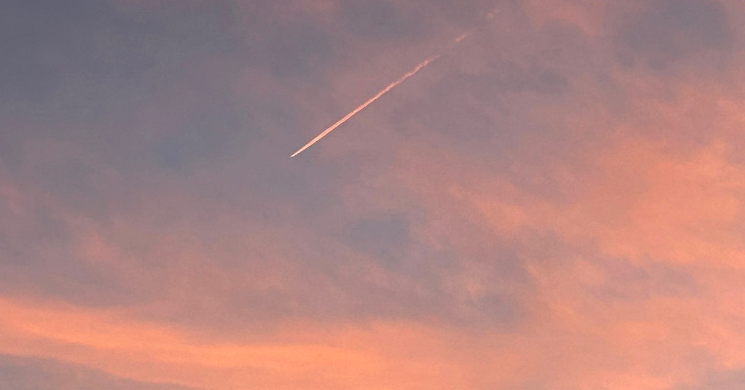 El cielo anocheciendo en tonos naranjas con algo que lo surca entre las nubes El cielo anocheciendo en tonos naranjas con algo que lo surca entre las nubes