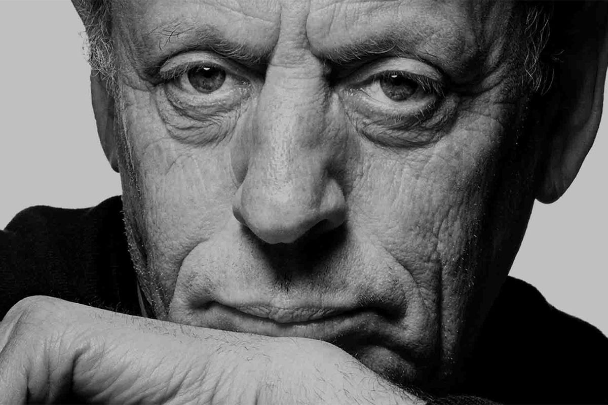 Black-and-white portrait of composer and pianist Philip Glass looking toward the camera.