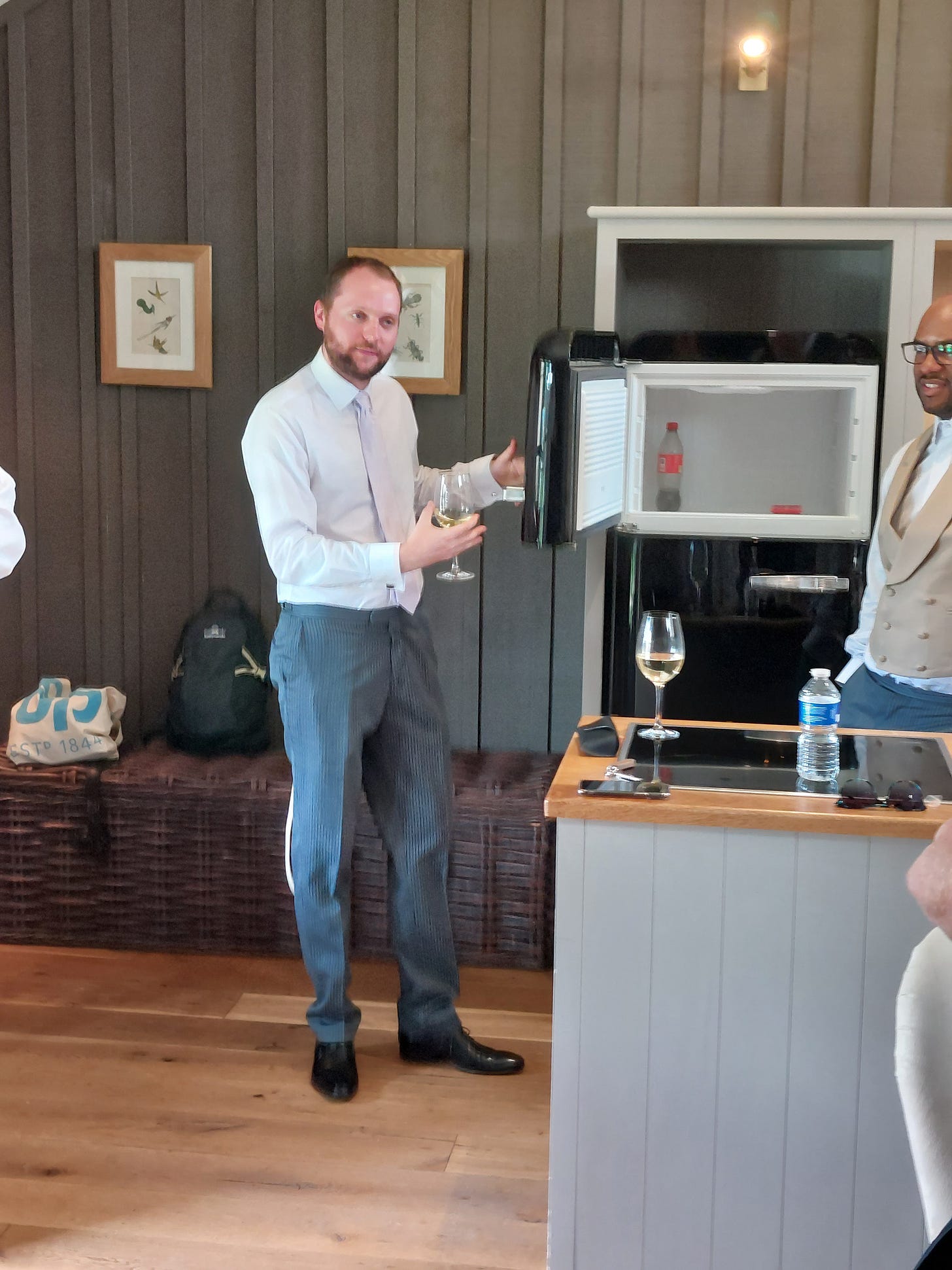A white man wearing very smart attire pretending to promote a Smeg fridge