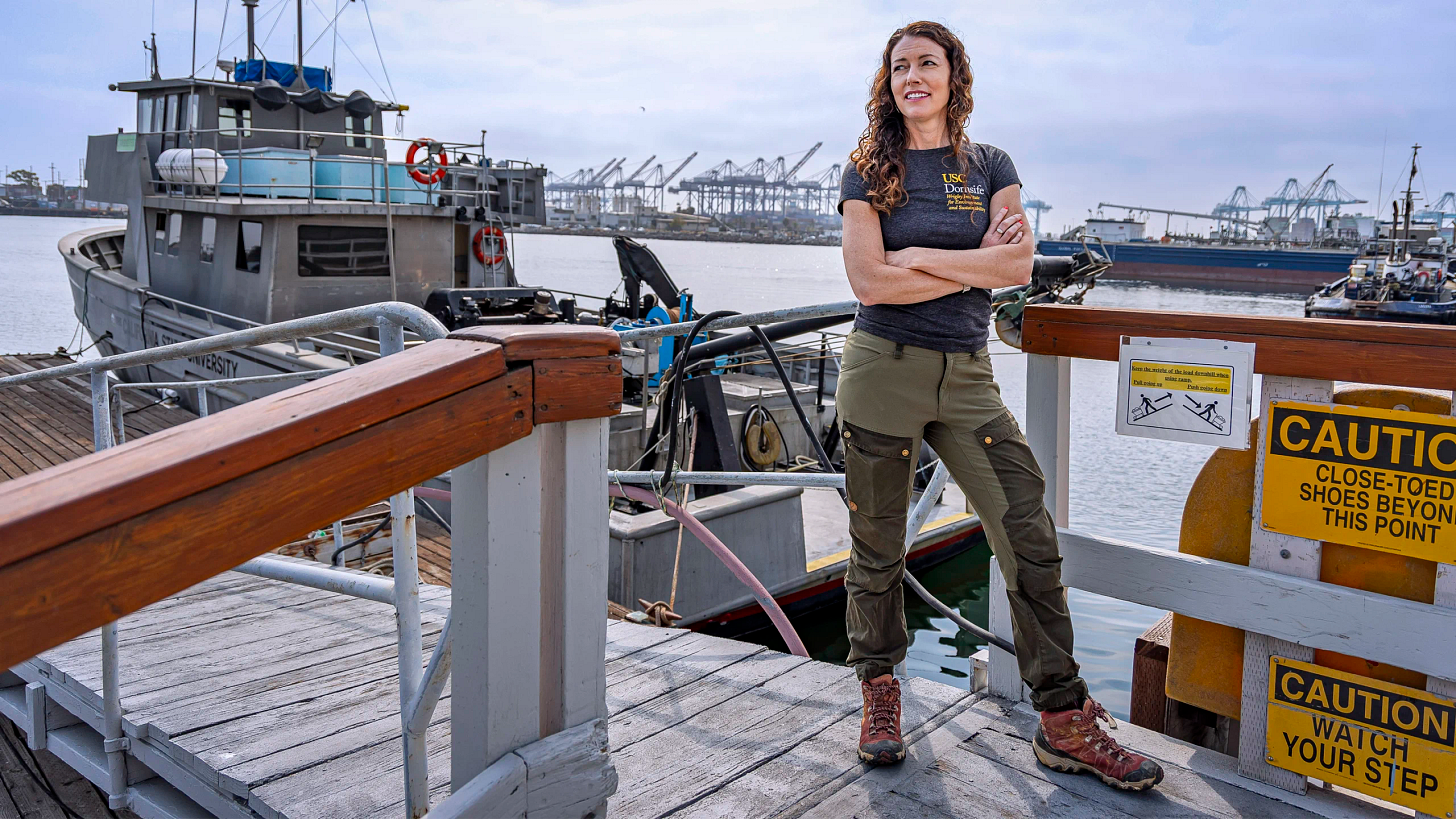 Lloyd stands on a dock in front of a research boat.