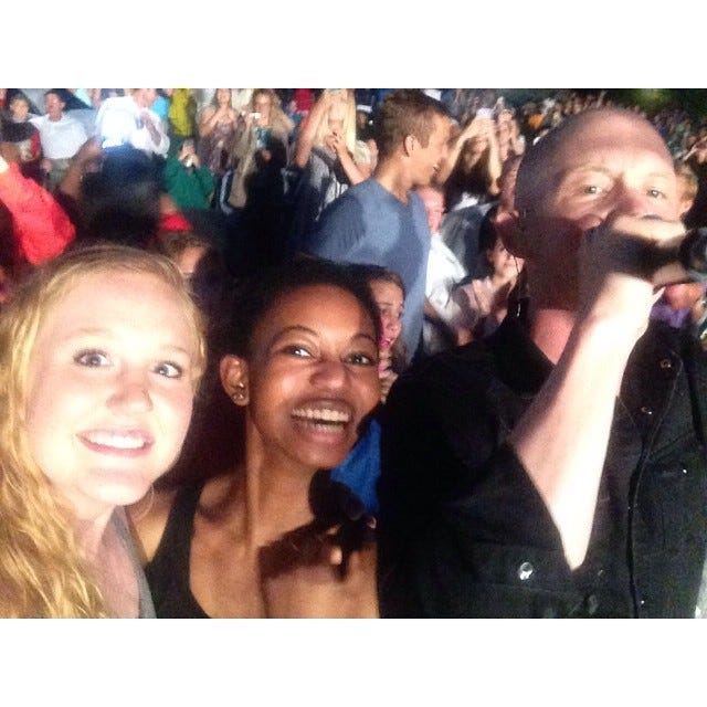 A photo of two people standing next to Isaac Slade from The Fray in concert