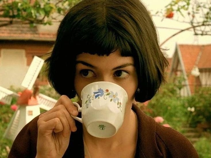 This may contain: a woman drinking from a white coffee cup