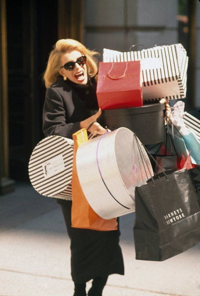 This may contain: a woman walking down the street carrying shopping bags and large suitcases on her back