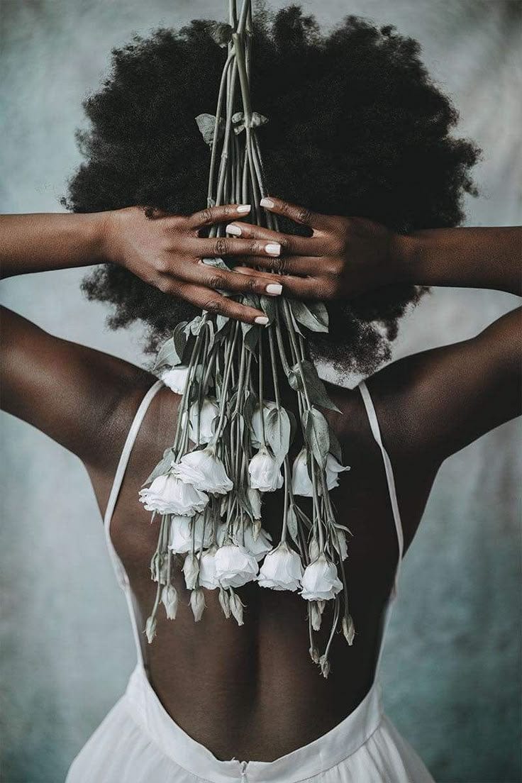 This may contain: a woman with her back to the camera holding flowers in front of her face and hands