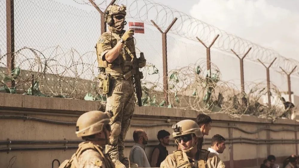 A Danish coalition service member holds up a Danish flag to identify families during an evacuation at Hamid Karzai International Airport, Kabul, Afghanistan, Aug. 21.