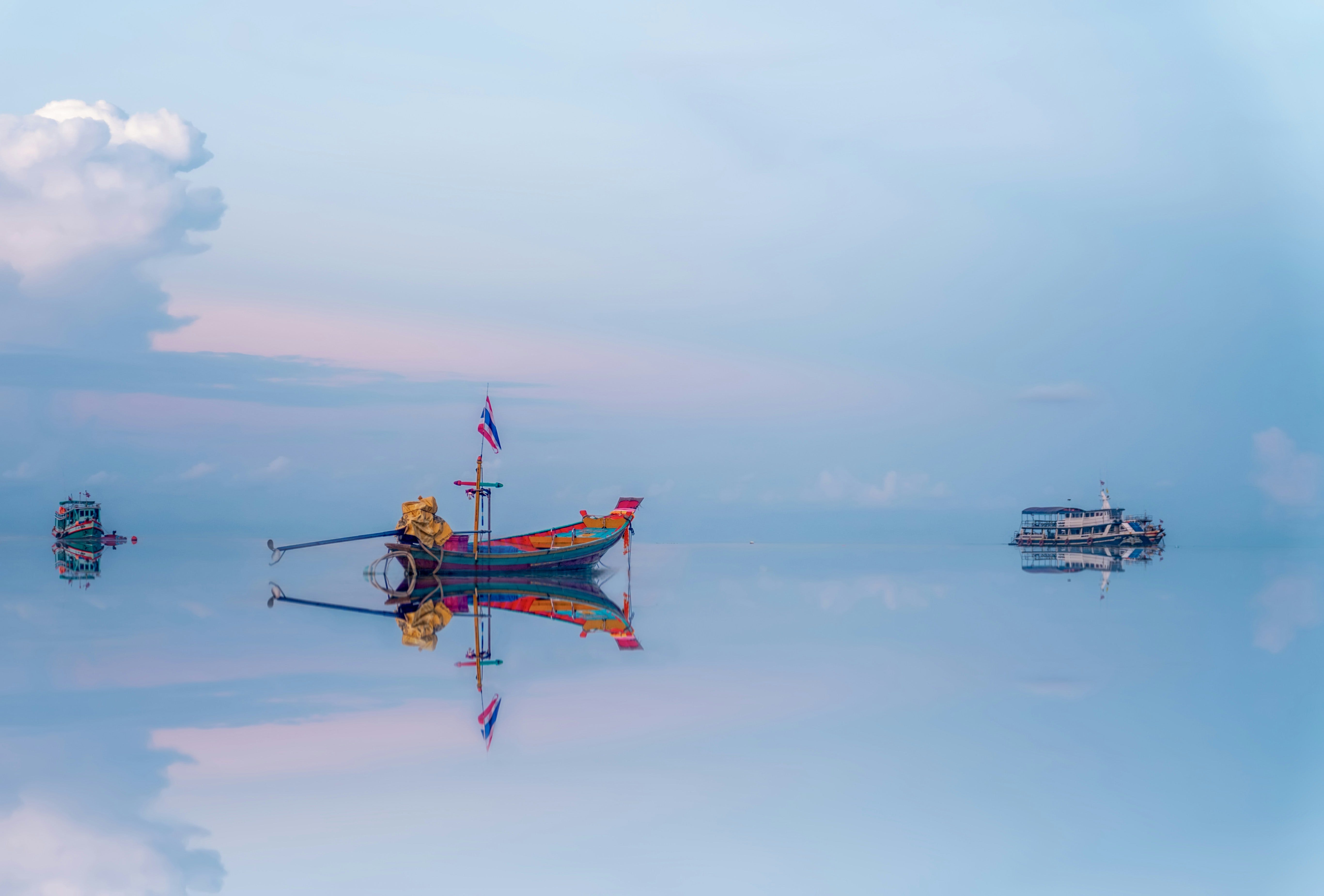 perfectly balanced image of 3 boats on blue sky reflected in blue water perfectly balanced image of 3 boats on blue sky reflected in blue water