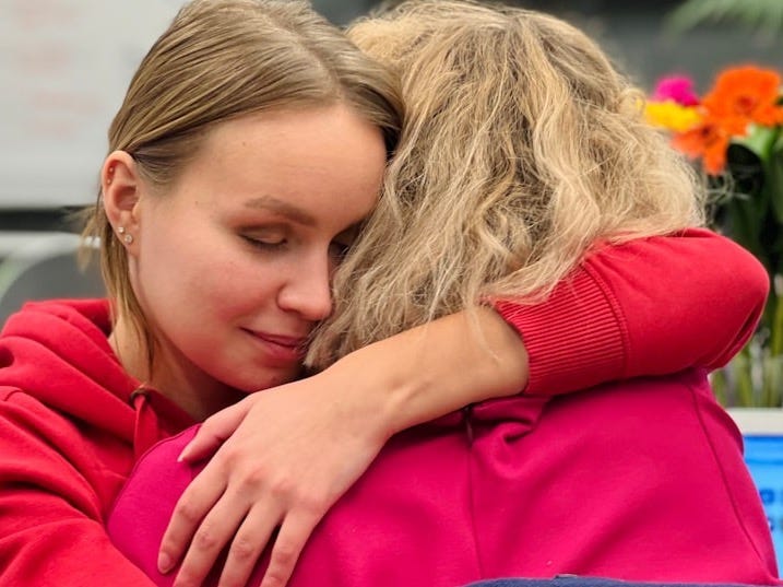 two women hugging each other in an office setting