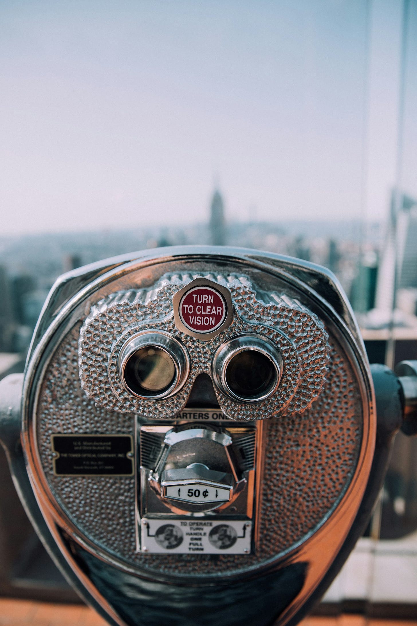A photo taken at the top of a tall building in a city, featuring one of the rooftop coin-operated binoculars, that will allow you to check out the view for 50 cents.