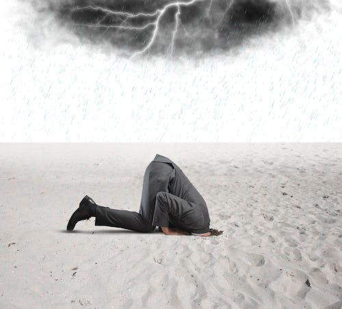 man hiding head in sand during thunderstorm