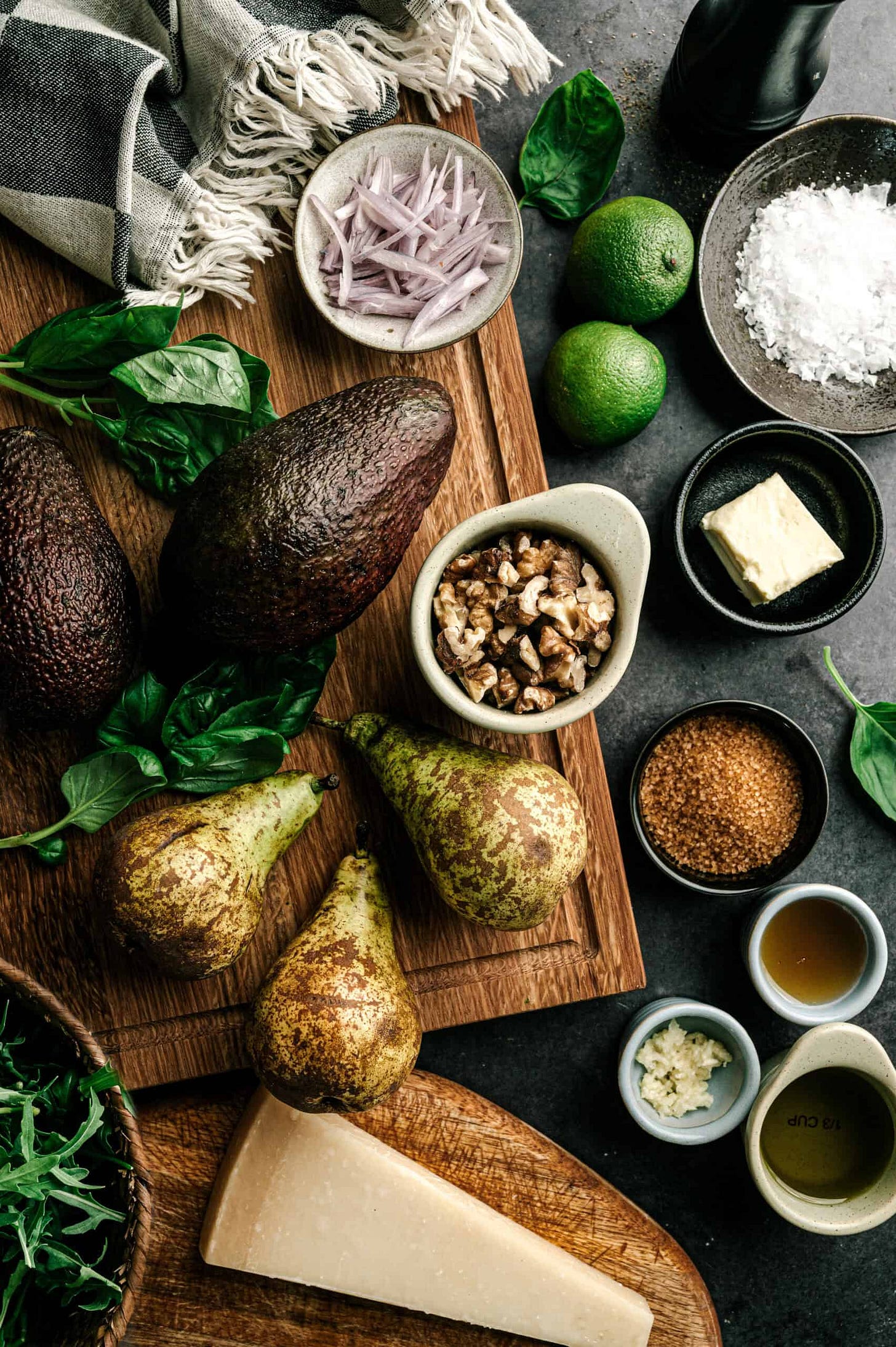 Key ingredients for avocado pear recipes featuring key ingredients on. cutting board; avocados, pears, walnuts, brown sugar, shallots, and lime, etc. 