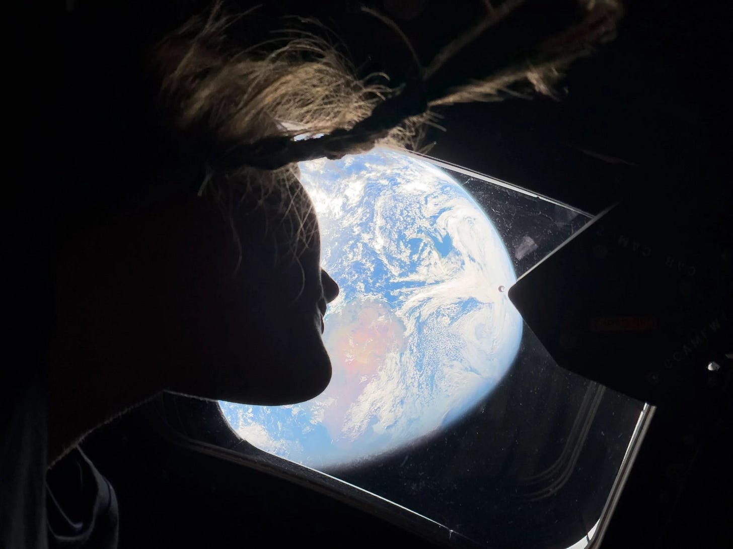 This image provided by NASA, astronaut and Artemis II mission specialist Christina Koch peers out of one of the Orion spacecraft's main cabin windows, looking back at Earth, as the crew travels towards the Moon on Thursday, April 2, 2026.