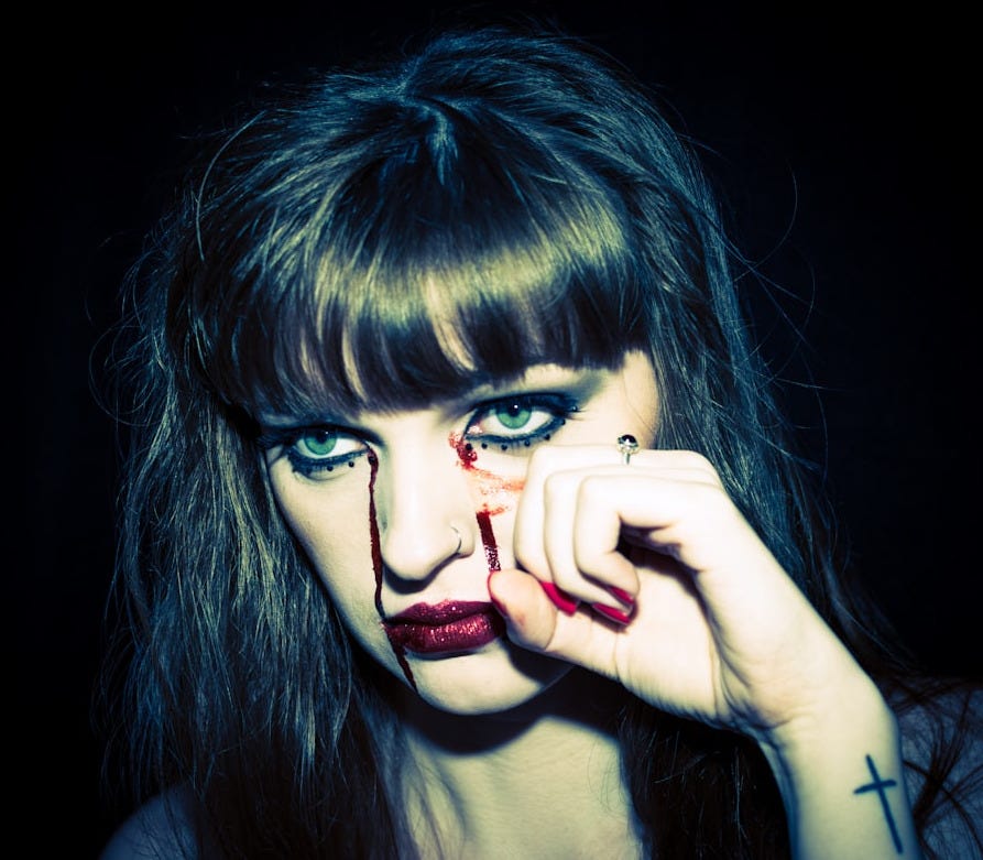 woman with left hand touching her face