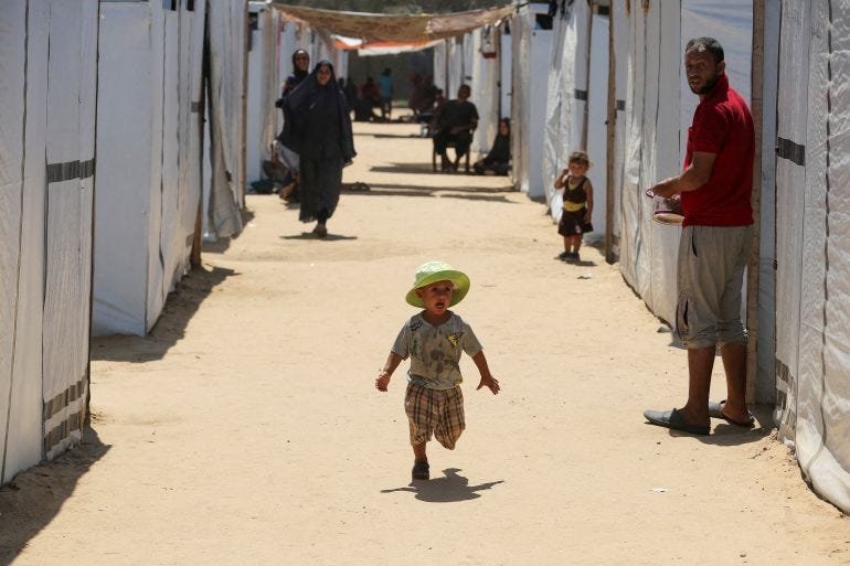 A displaced Palestinian boy runs in a tent camp designated for people with special needs, amid the Israel-Hamas conflict, in Deir Al-Balah in the central Gaza Strip August 8, 2024. REUTERS/Hatem Khaled REFILE - CORRECTING INFORMATION FROM "A BOY RUNS WITH AN AMPUTATED LEG" TO "A BOY RUNS