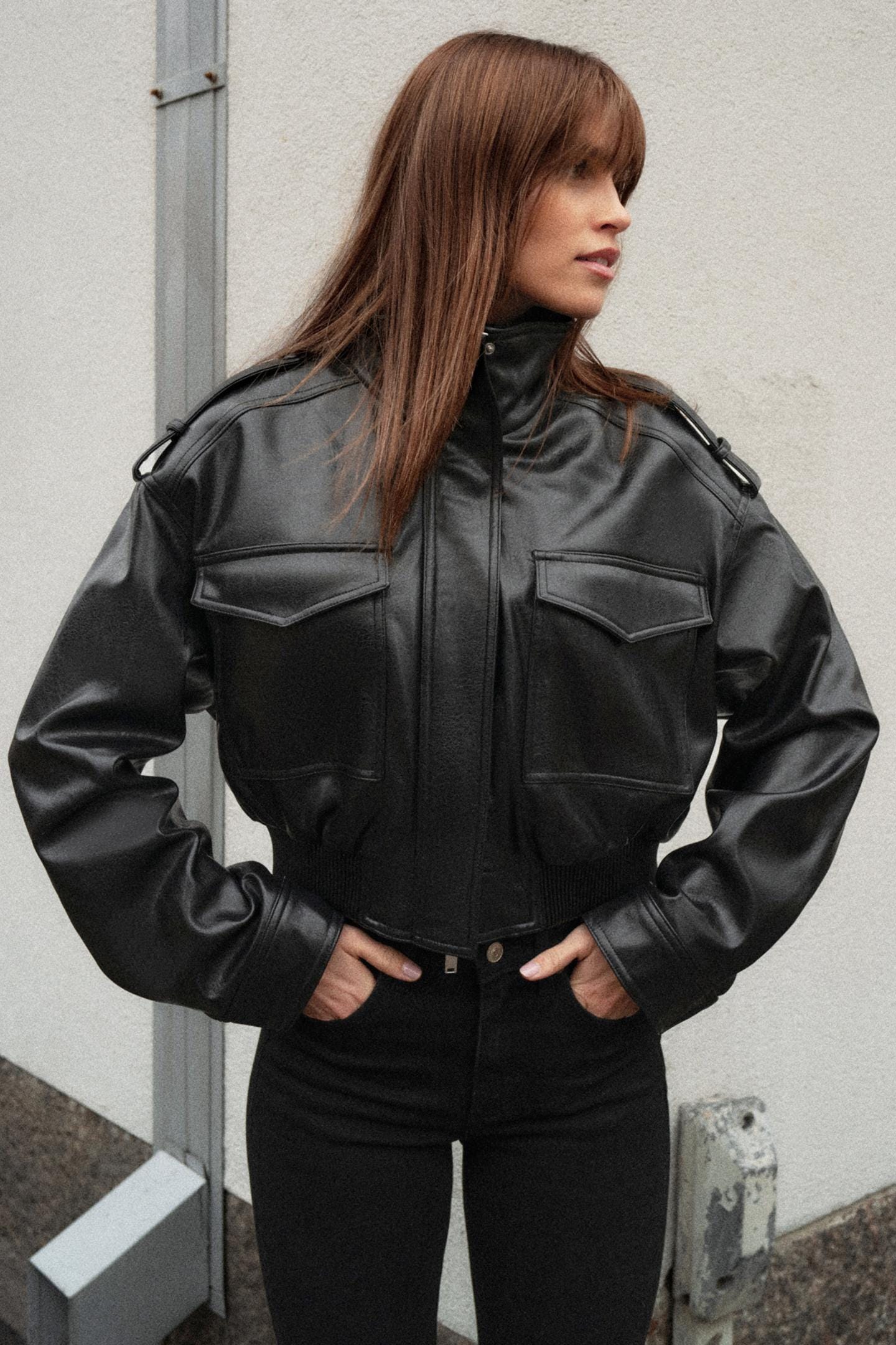 Black bomber jacket and slim-fit black trousers with front flap pockets.