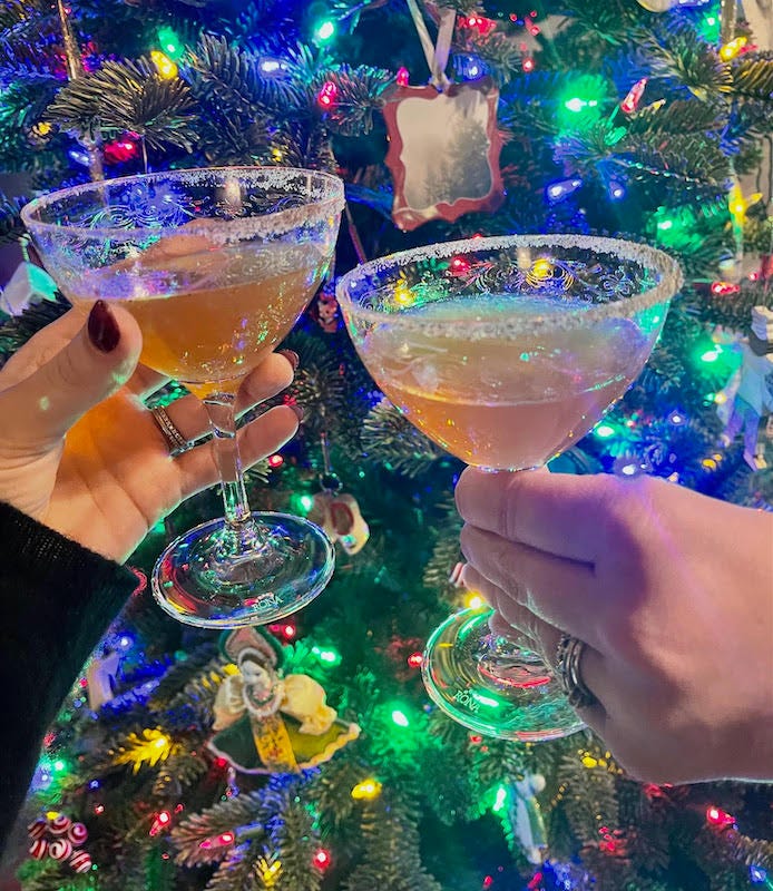 Two people clinking their glasses filled with fruitcake cocktail in front of a Christmas tree Two people clinking their glasses filled with fruitcake cocktail in front of a Christmas tree