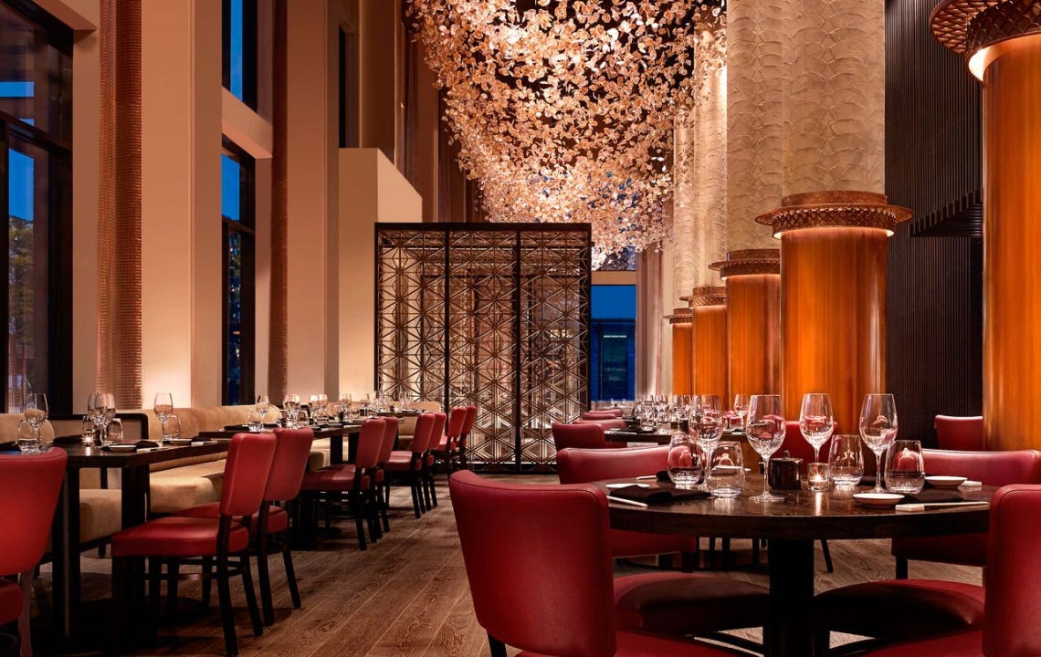 towering chandelier in a high-ceilinged restaurant with red leather chairs and luxurious fixtures towering chandelier in a high-ceilinged restaurant with red leather chairs and luxurious fixtures