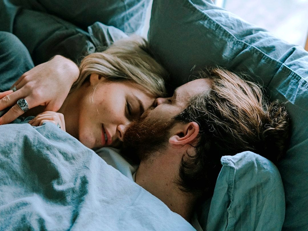 man kissing woman's forehead while lying on bed man kissing woman's forehead while lying on bed