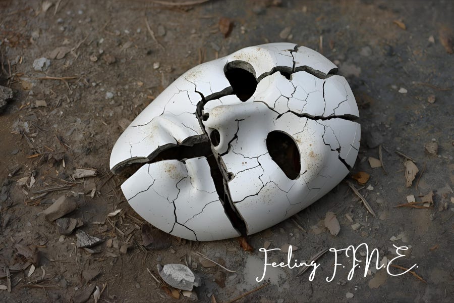 A white porcelain mask lies on gritty ground, split into deep cracks. Script at the bottom reads “Feeling F.I.N.E.”